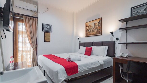Habitación de hotel con cama, escritorio, silla, teléfono y aire acondicionado de pared.