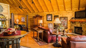 A cozy log cabin interior with a fireplace, leather furniture, and wooden beams on the ceiling. - ✧Royale Cabin- KING bed, hot tub, NO CLEANING FEE (Dryfork)