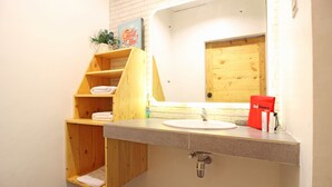 A bathroom with a wooden vanity, a sink, and a mirror. There is a towel rack and a red bag on the counter. - RedDoorz near Pojok Beteng Prawirotaman (Yogyakarta)