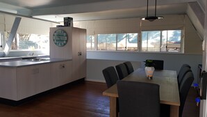 A modern kitchen with a central island, a dining table with chairs, and a clock on the wall.