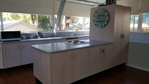 A modern kitchen with a central island, a built-in stove, a microwave, and a clock on the wall.