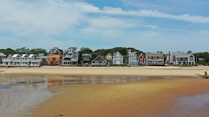 Ein Strandhaus mit Sandstrand, einer Reihe von Häusern und einem klaren Himmel.
