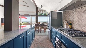 Eine moderne Küche mit Fischgrätparkett, einem Gasherd und Blick ins Freie.