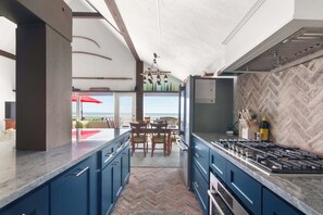 A modern kitchen with a herringbone floor, a gas stove, and a view to the outside. - Beachfront on Commercial St w/ Water Views! (Provincetown)