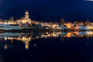 Une ville située au bord de l’eau, avec une église imposante et des immeubles d’habitation dont les façades se reflètent dans l’eau.