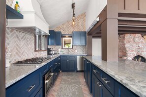 Eine Küche mit blauen Schränken, einem Gasherd und einem Backofen aus Ziegeln.