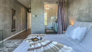 Une chambre moderne avec un grand lit, une table de chevet, un miroir et une vue sur un balcon.