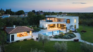 Une maison moderne à deux étages, dotée d’une piscine, d’un espace extérieur aménagé et d’un jardin bien entretenu.