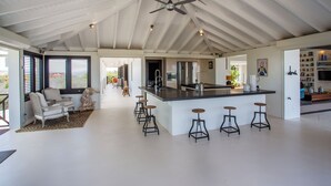 A spacious kitchen with a central island, bar stools, and a ceiling fan. - Amazing 360 views over the Caribbean Sea, 12 guests and private pool (Sint Willibrordus)