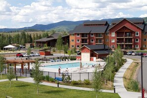 Un resort con piscina, edificios de varios pisos y montañas al fondo.