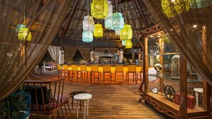 An interior with a bar area, wooden flooring, and hanging lanterns.