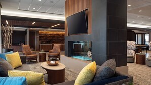 A modern lobby with a large TV, comfortable seating, a fireplace, and a bar area. - Courtyard by Marriott Loveland Fort Collins (Loveland)