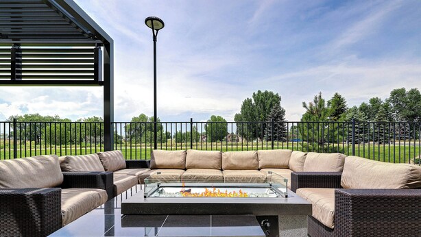 An outdoor patio with a glass-top table, wicker furniture, and a fire feature. - Courtyard by Marriott Loveland Fort Collins (Loveland)