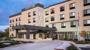 A modern hotel with a courtyard entrance, multiple floors, and a flag. - Courtyard by Marriott Loveland Fort Collins (Loveland)