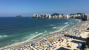 Una playa con un horizonte urbano al fondo, que incluye rascacielos y una isla distante.
