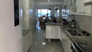 Una cocina moderna con armarios blancos, encimera de granito y cocina a gas.