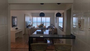 Una cocina moderna con comedor, ventanas amplias y vista al mar.