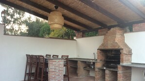 An outdoor patio with a brick barbecue and a table with chairs. - Lake Vinuela peaceful holiday in beautiful surroundings  (Los Romanes)