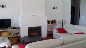 A living room with a fireplace, a sofa, a television, and a small table. - Lake Vinuela peaceful holiday in beautiful surroundings  (Los Romanes)