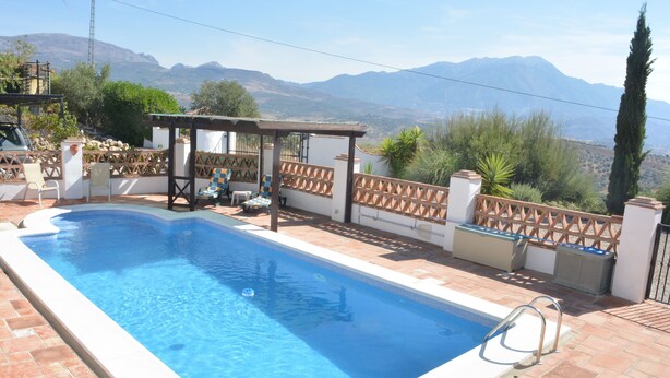 A rectangular swimming pool with a wooden deck and a pergola, surrounded by a fence and plants. - Lake Vinuela peaceful holiday in beautiful surroundings  (Los Romanes)