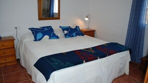A bedroom with a bed, a bedside table, a lamp, a mirror, and a window with curtains. - Lake Vinuela peaceful holiday in beautiful surroundings  (Los Romanes)