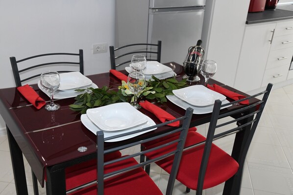 A dining table set with white plates, red napkins, and clear glasses. - City Heart Luxury studios (Rodos)