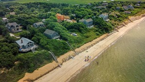 Vista aérea de uma área residencial costeira com casas, praia e litoral rochoso.