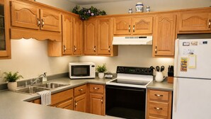 A kitchen with wooden cabinets, a stainless steel sink, a microwave, a stove, and a refrigerator.