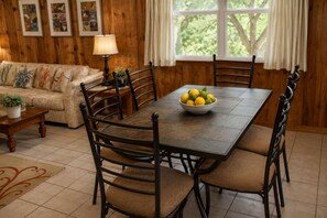 Uma sala de jantar com uma mesa de madeira, cadeiras e uma tigela de frutas.