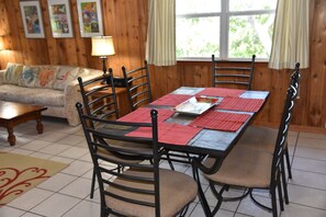 A dining area with a wooden table, chairs, and a sofa. - Z House | Shaded Coastal Hideaway on the dunes (Dauphin Island)