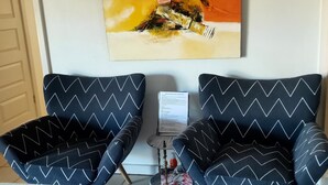 Two black chairs with white zigzag patterns, a painting on the wall, and a small table with a floral tablecloth. - Sanctuary for family and friends (Balcatta)