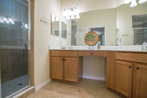 Une salle de bain avec une douche, un lavabo avec un miroir et des meubles en bois.