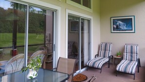A sunlit patio with a glass table, striped chairs, and a framed picture of a tiger. - Unique style 2 BR/2 BA townhouse in Disney Area (Kissimmee)