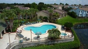 A residential area with a swimming pool surrounded by a fence, palm trees, and houses. - Unique style 2 BR/2 BA townhouse in Disney Area (Kissimmee)