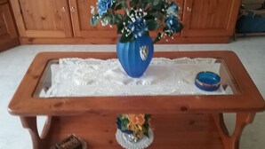 A wooden table with a vase of flowers and a small decorative item on the center.