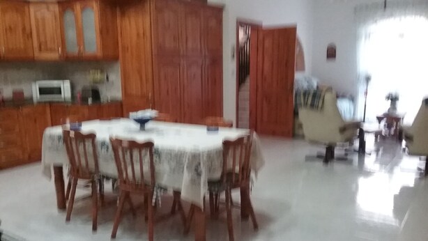 A dining area with a round table and chairs, wooden cabinets, and a microwave.