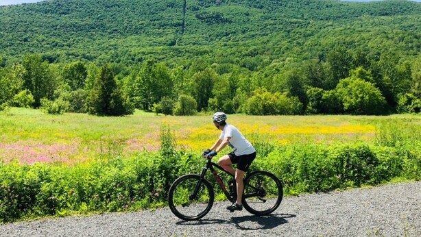 Un ciclista en un camino de grava con montañas al fondo.