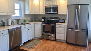 Una cocina moderna con armarios blancos, electrodomésticos de acero inoxidable y piso de madera.
