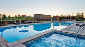 Ein rechteckiger Pool mit Fliesenrand, umgeben von Liegestühlen und einer Steinmauer.