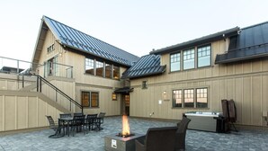 Eine Außenpatio mit Feuerstelle, Sitzgelegenheiten und Whirlpool.