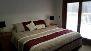 A bedroom with a large bed, two bedside tables, and a window with blinds.