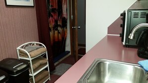 A kitchen with a sink, a microwave, and a white shelf with towels.