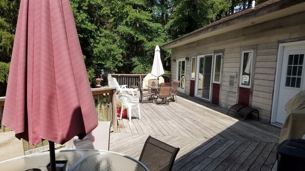 A wooden deck with outdoor furniture, including a table and chairs, and a covered area with a table and chairs.