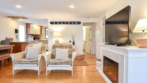 A cozy living room with a fireplace, two armchairs, a television, and a sign that reads "CHATHAM". - Lovely Home Minutes from Beach in Chatham! (Chatham)
