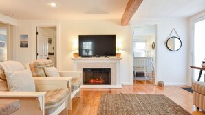 A living room with a fireplace, a television, and a sofa. - Lovely Home Minutes from Beach in Chatham! (Chatham)