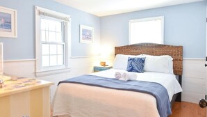 A bedroom with a bed, a nightstand, a dresser, and a window. - Lovely Home Minutes from Beach in Chatham! (Chatham)