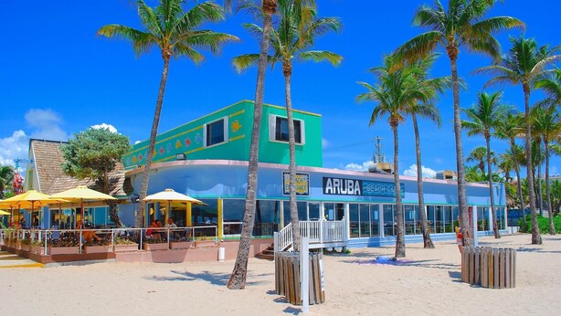 A beachside building with a green and blue facade, palm trees, and outdoor seating areas. - BY THE SEA VACATION VILLAS 3 BED POOL/ BEACH AT END OF STREET (Lauderdale-by-the-Sea)
