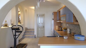 Cocina con encimera de madera, un lavamanos y un microondas. Se ve una escalera que sube a otro nivel.