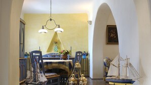 Un comedor con una mesa dispuesta para dos, una araña y modelos de barcos.