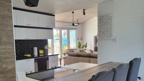 A modern kitchen with white cabinets, a wooden countertop, and a dining area with a large table and chairs. - Spectacular Views at the Lakehouse Paradise!! (Toa Baja)